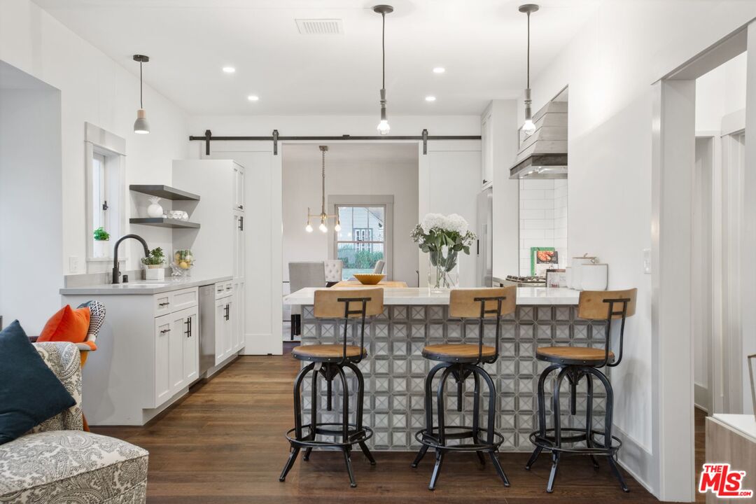 403 North Irving Boulevard Los Angeles, CA 90004 - Photo 26 of 46 a kitchen with stainless steel appliances kitchen island granite countertop a table chairs sink and wooden floor