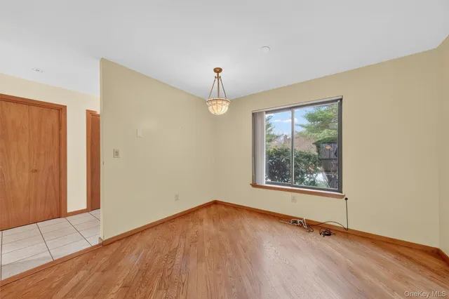 a view of an empty room with window and wooden floor