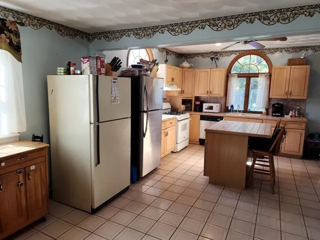 a kitchen with stainless steel appliances granite countertop a refrigerator a sink a stove and a refrigerator