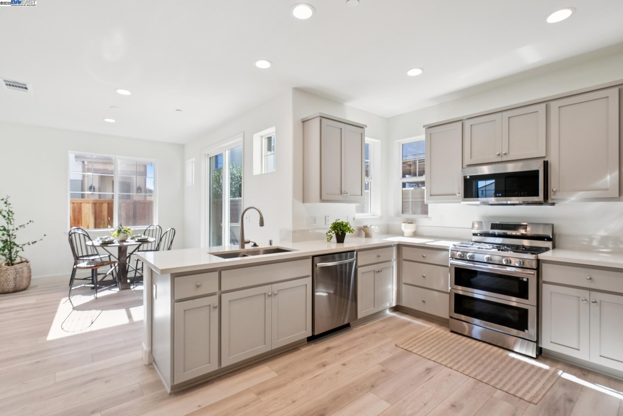 246 Mindy Way Pittsburg, CA 94565 - Photo 11 of 38 a kitchen with stainless steel appliances granite countertop a stove top oven a sink dishwasher a dining table and chairs with wooden floor