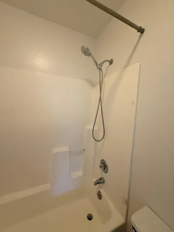 a bathroom with a shower and a white bath tub