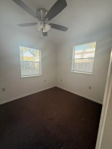 an empty room with a window and a fan