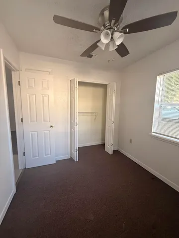an empty room with windows and fan