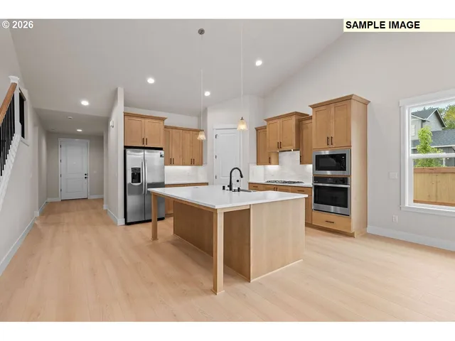 a open kitchen with stainless steel appliances kitchen island a sink dishwasher a refrigerator and white cabinets with wooden floor