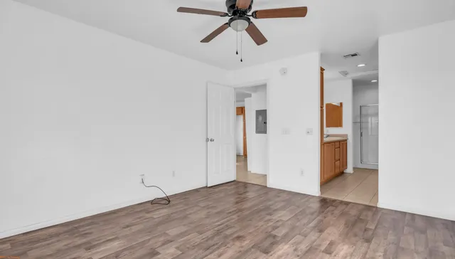 a view of an empty room with wooden floor and a window