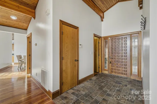 a view of an empty room with wooden floor and a chandelier