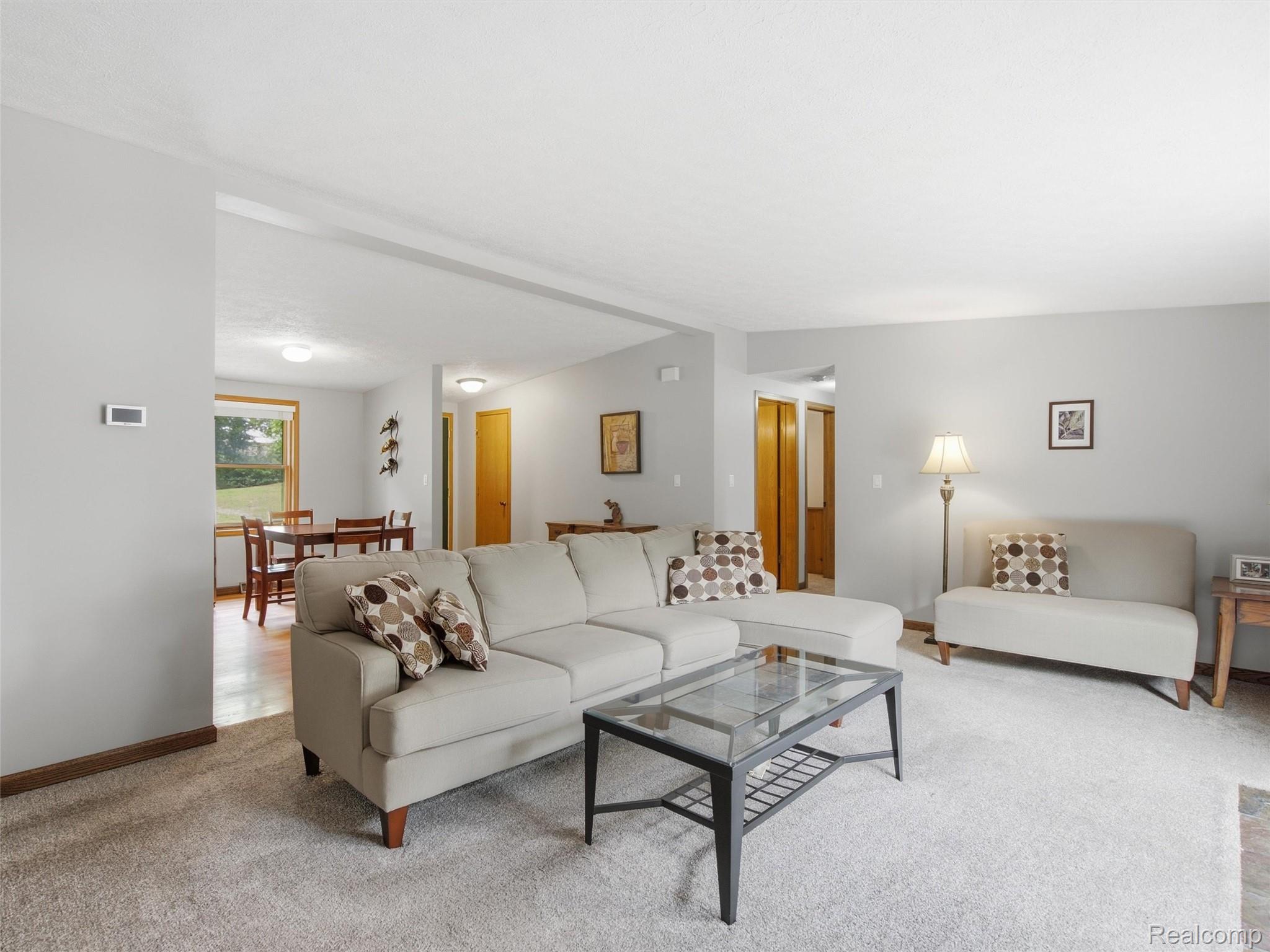 5003 Mason Road Howell, MI 48843 - Photo 7 of 59 Open-concept living space featuring light gray walls, carpet flooring, a central ceiling light fixture, and a thermostat