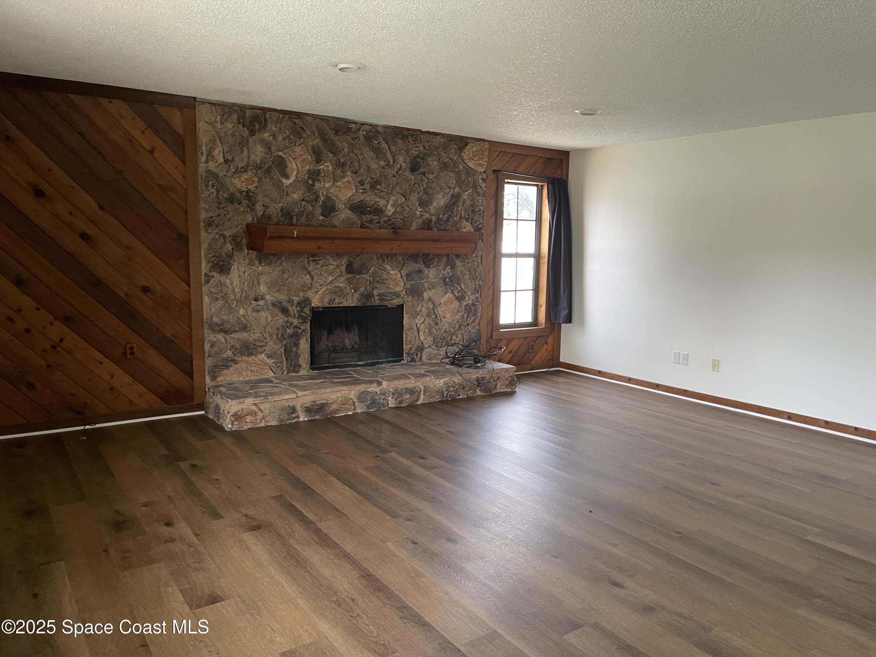 3445 Fox Lake Road Titusville, FL 32780 - Photo 8 of 43 an empty room with wooden floor fireplace and windows
