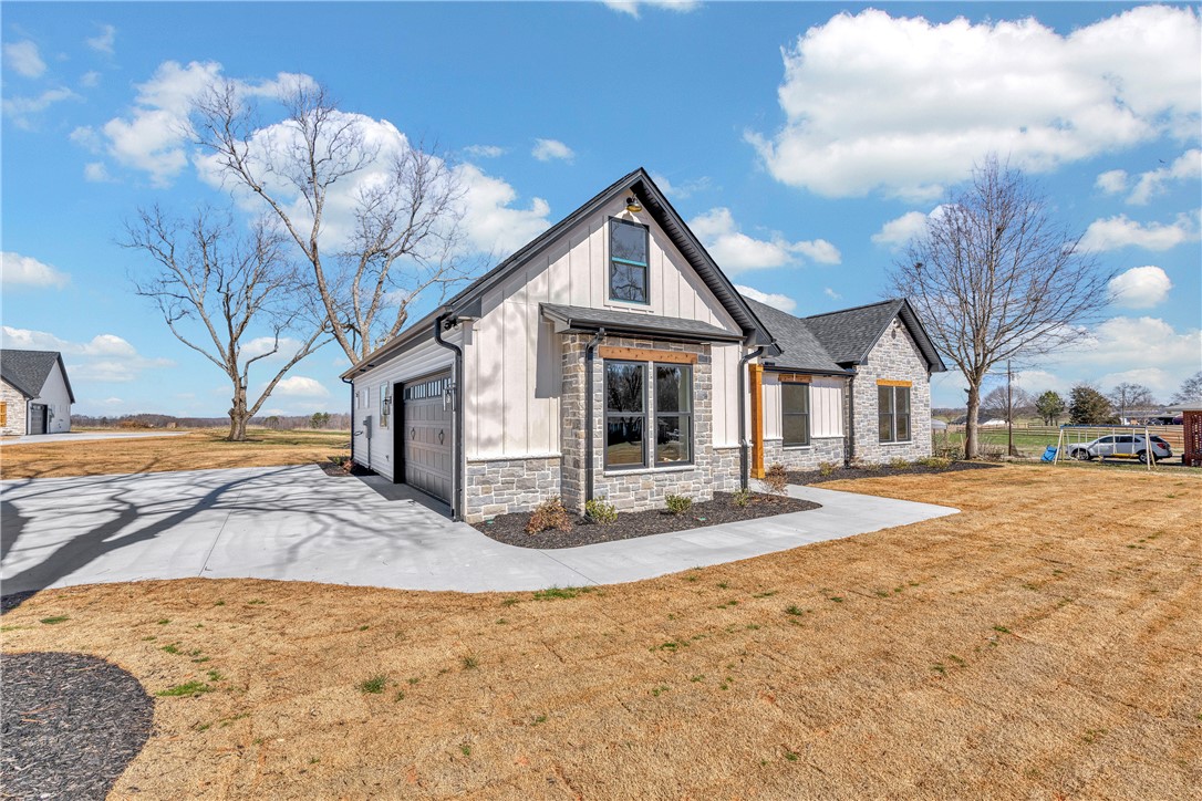 2816 Smith McGee Road Iva, SC 29655 - Photo 5 of 25 A stylish home showcasing a garage and a stone and siding facade, set amidst a spacious yard.
