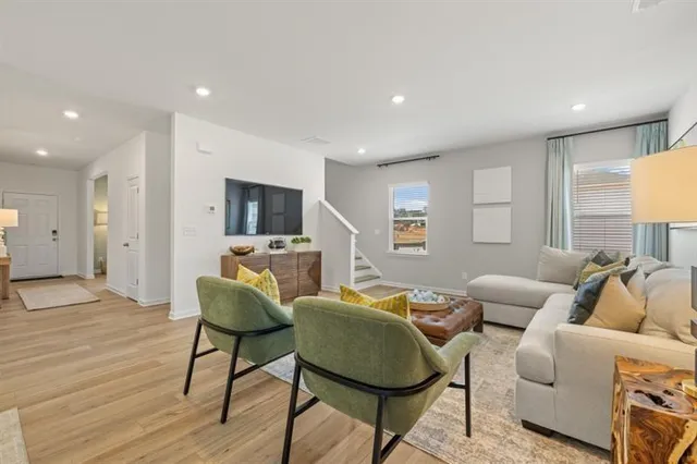 a living room with furniture kitchen view and a large window
