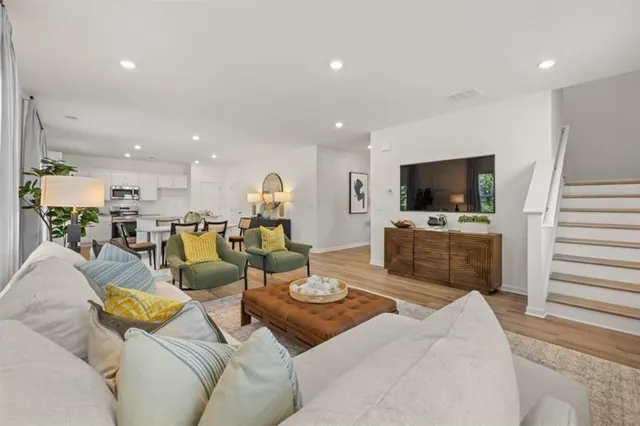a view of a hallway to a livingroom with wooden floor and furniture