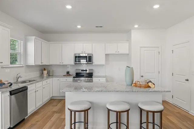 a kitchen with stainless steel appliances granite countertop a kitchen island stools a stove a sink dish washer and a refrigerator