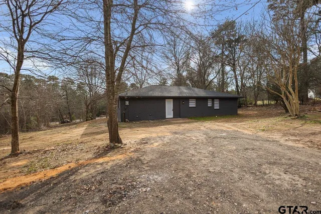 a view of a house with a yard and large tree