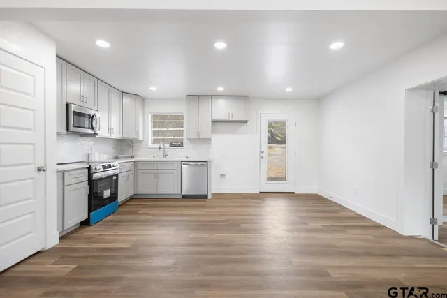 a large kitchen with cabinets wooden floor and stainless steel appliances