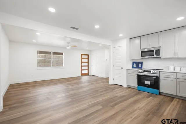 a large kitchen with stainless steel appliances granite countertop a stove and a wooden floors