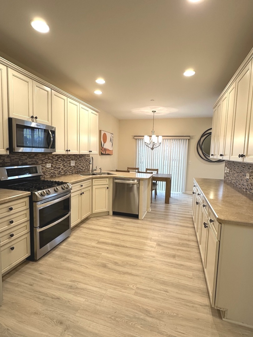 5102 Monroe Street Matteson, IL 60443 - Photo 17 of 54 a large kitchen with stainless steel appliances granite countertop a stove a sink and a microwave