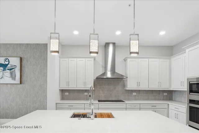 a kitchen with a white center island a stove a refrigerator cabinets and a fireplace