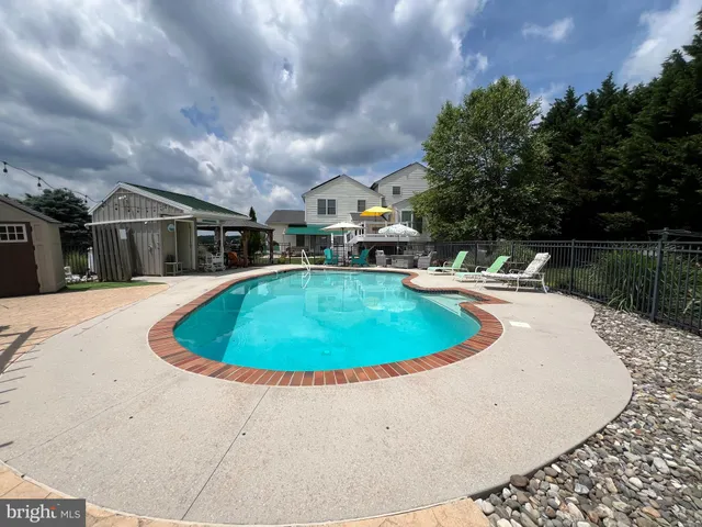 a swimming pool with outdoor seating and yard in back