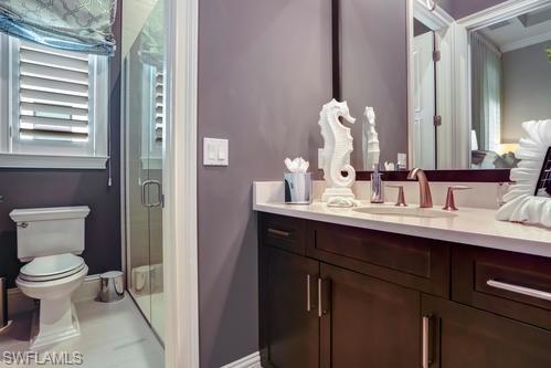 595 Regatta Road Naples, FL 34103 - Photo 27 of 40 Bathroom featuring a dark wood-finish vanity with a light countertop, an undermount sink, and a three-piece faucet