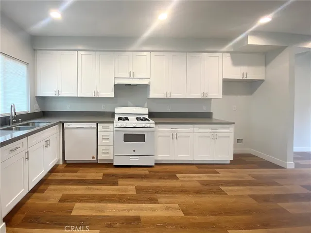 a kitchen with stainless steel appliances granite countertop a stove a sink and white cabinets