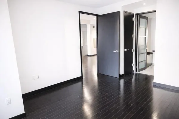 a view of an empty room with wooden floor and closet
