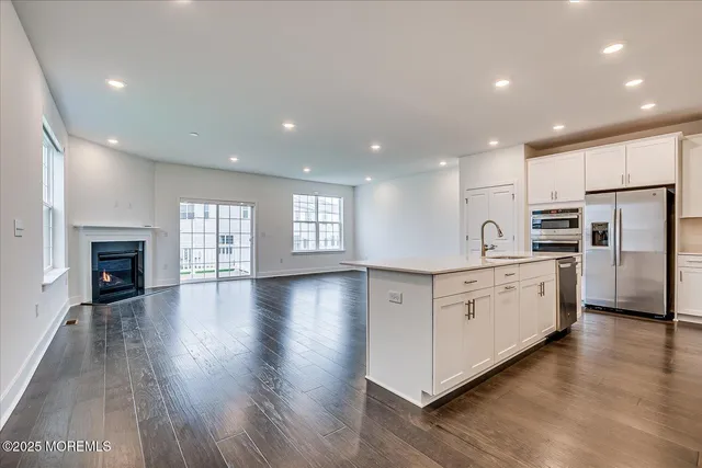 a large kitchen with white cabinets stainless steel appliances a window and a fireplace