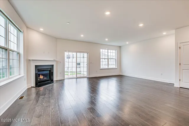 an empty room with wooden floor fireplace and windows