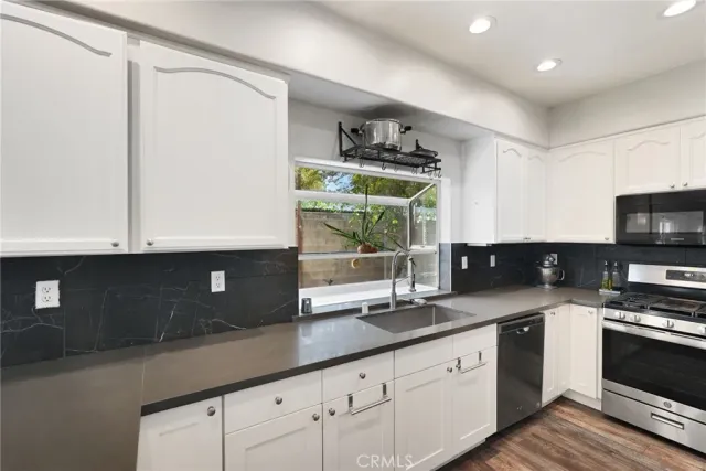 a kitchen with stainless steel appliances a refrigerator a sink and white cabinets