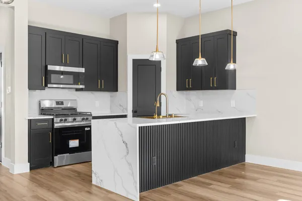 a kitchen with stainless steel appliances kitchen island hardwood floor sink and stove