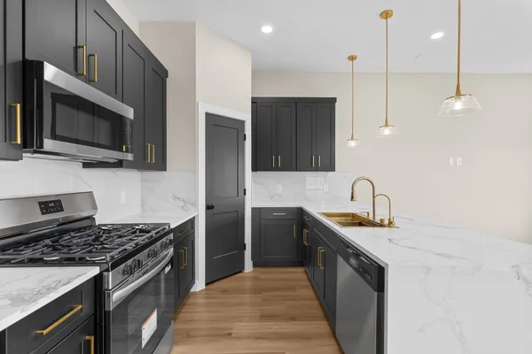 a kitchen with stainless steel appliances granite countertop a stove a sink and a microwave