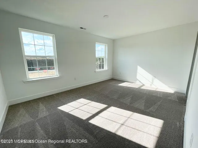 a view of an empty room with wooden floor and windows
