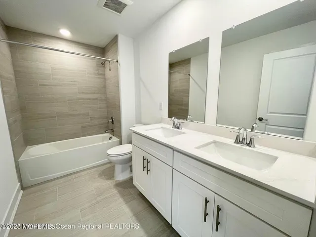 a bathroom with a double vanity sink toilet mirror and bathtub