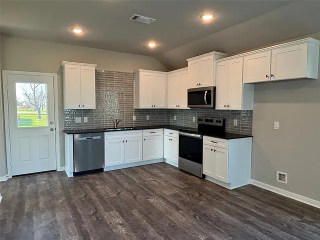 a kitchen with granite countertop white cabinets and black stainless steel appliances