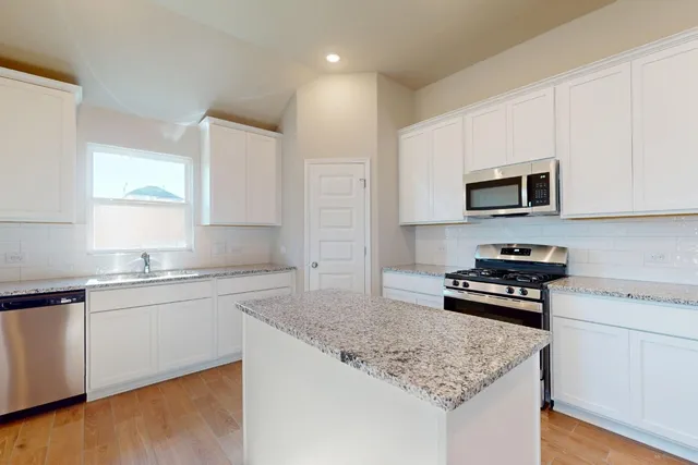 a kitchen with stainless steel appliances granite countertop a sink stove and microwave
