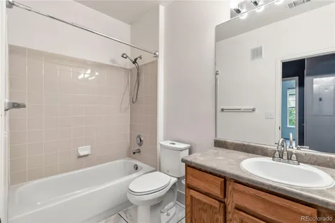 a bathroom with a granite countertop sink toilet mirror and bathtub