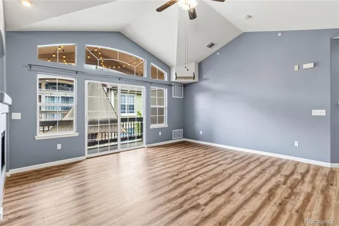 a view of an empty room with wooden floor and a fireplace