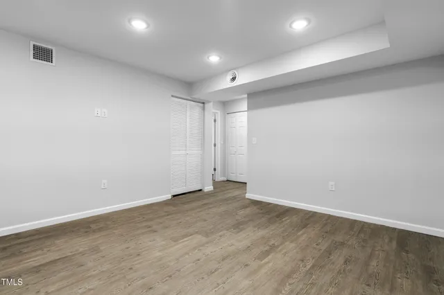 an empty room with wooden floor and white walls