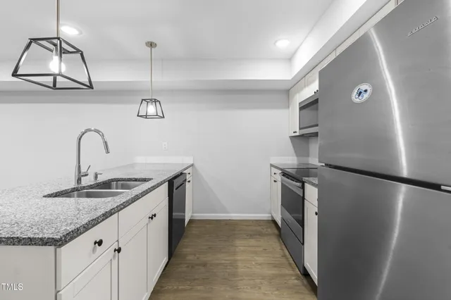 a kitchen with granite countertop a table chairs refrigerator and microwave