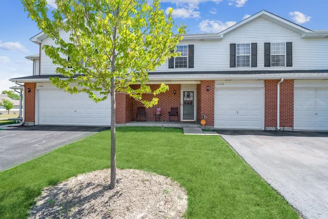 a view of a white house with a small yard and large tree