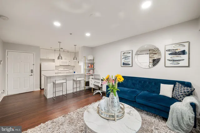a living room with stainless steel appliances furniture and wooden floor