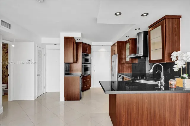 a kitchen with stainless steel appliances kitchen island granite countertop a refrigerator and a sink