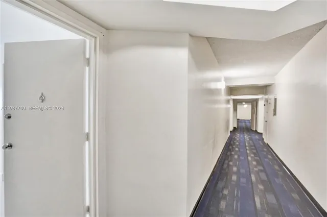a view of a hallway with wooden floor and a bathroom