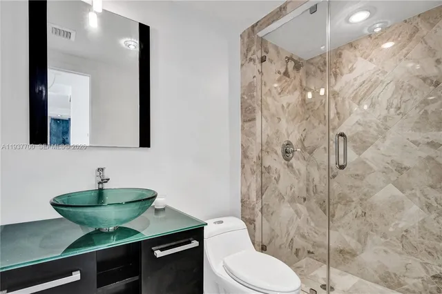 a bathroom with a granite countertop sink toilet a mirror and shower curtain