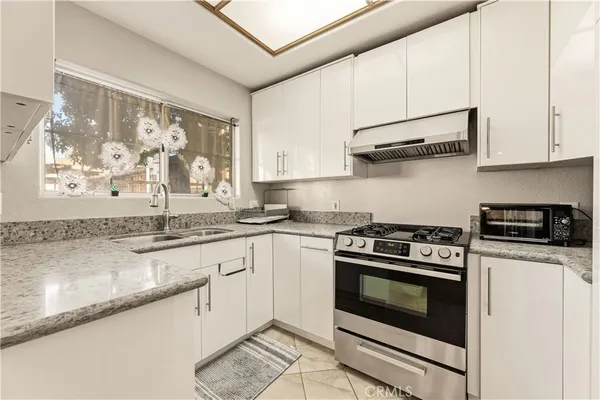 a kitchen with stainless steel appliances granite countertop white cabinets and a granite counter tops with a large window