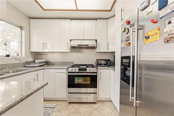 a kitchen with stainless steel appliances granite countertop a refrigerator sink and stove