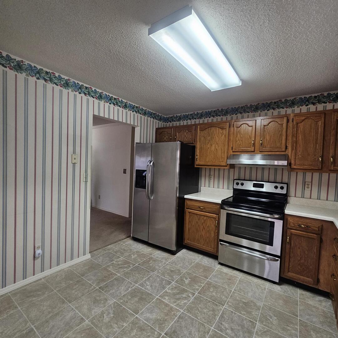 4412 Woodglen Lane Mount Vernon, IL 62864 - Photo 21 of 35 a kitchen with granite countertop a refrigerator and a stove top oven