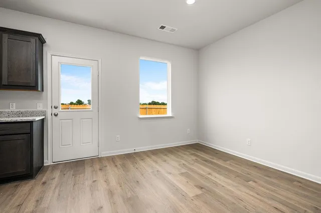 a view of an empty room with a window and wooden floor