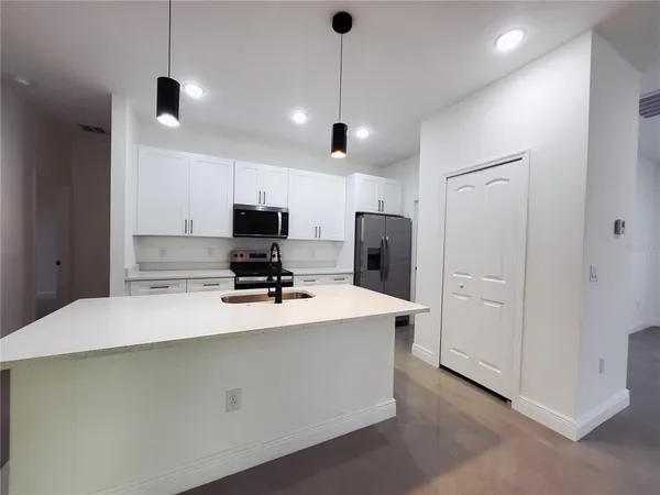a kitchen with stainless steel appliances a refrigerator sink and white cabinets
