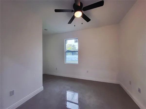 an empty room with a window and a fan