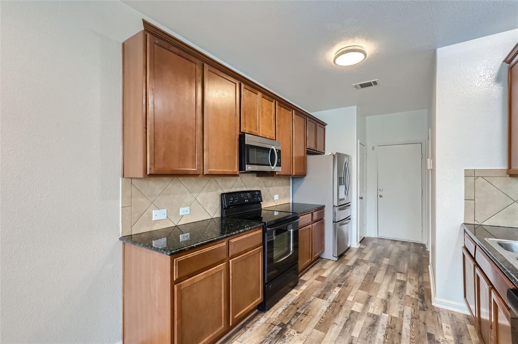 131 Lavaca Loop Hutto, TX 78634 - Photo 6 of 29 A well-appointed culinary space featuring sleek black appliances and rich wood cabinetry.